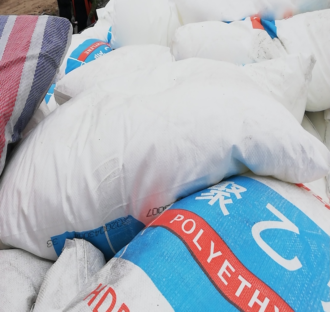 Side-view-of-stacked-Shenhua-HDPE-resin-white-woven-bags-in-bulk-warehouse-stock